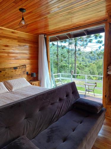 a bedroom with a bed and a large window at Recanto do Ipê cabana 01 in Urubici