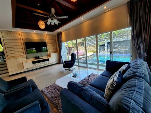 a living room with a blue couch and a tv at I am pool villa Pattaya no14 in Ban Nong Phlap