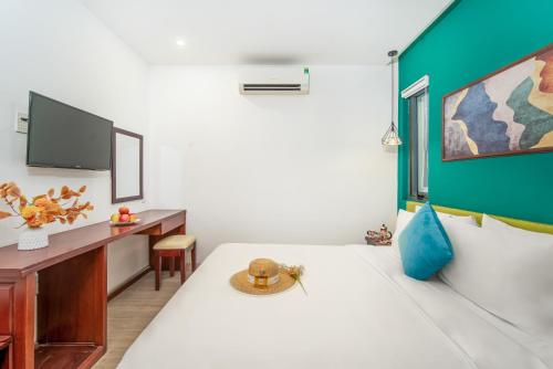 a room with a bed and a desk and a tv at May Beach Hotel in Danang