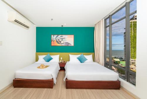 two beds in a room with a green wall at May Beach Hotel in Da Nang