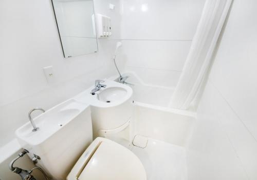 a white bathroom with a toilet and a sink at TKP Sunlife Hotel in Fukuoka