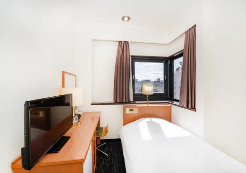 um quarto de hotel com uma cama e uma televisão em TKP Sunlife Hotel em Fukuoka