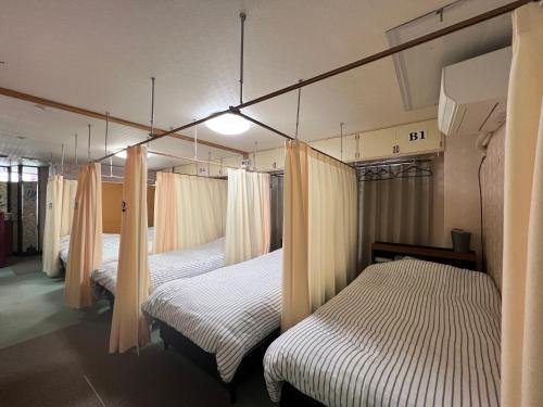 1 dormitorio con 4 camas con cortinas en ゲストハウス　アロマ, en Ureshino