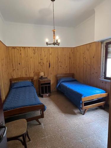 1 dormitorio con 2 camas y lámpara de araña en Chalet en Mar del Plata en Mar del Plata