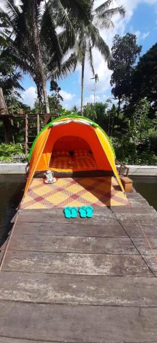 a tent and pair of blue flip flops on a dock at Omah Kepel Yogyakarta in Soprayan