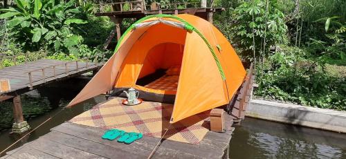 an orange tent on a boat in the water at Omah Kepel Yogyakarta in Soprayan