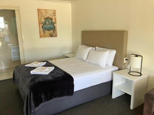 a hotel room with a bed and a night stand at Porky's Motel Rockhampton in Rockhampton