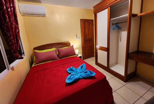 Fare Moana Bord de Mer Fare Tepua Lodge في أوتوروا: غرفة نوم بها سرير احمر وعليه قوس ازرق
