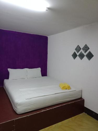 a white bed in a room with a purple wall at Som PalmGarden in Ko Lanta