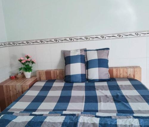 a bed with a blue and white blanket and pillows at Nhà nghỉ Út Tí in Tân Tạo