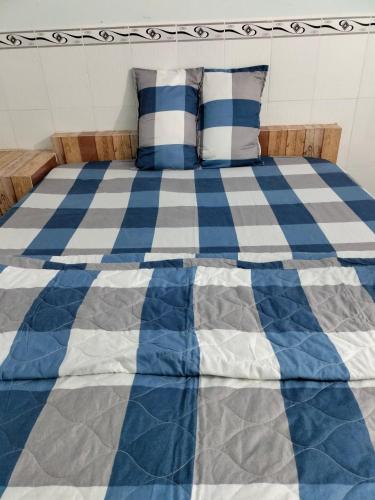 ein blau-weißes Bett mit Kissen darauf in der Unterkunft Nhà nghỉ Út Tí in Tân Tạo