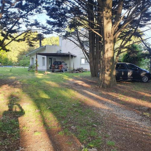 un coche aparcado frente a una casa con un árbol en Casa con pileta en Pinares de Santa Clara, en Santa Clara del Mar
