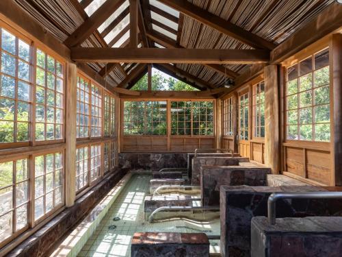 uma vista interior de um quarto com mesas e janelas em Tennenonsen Harunonoyu em Kochi