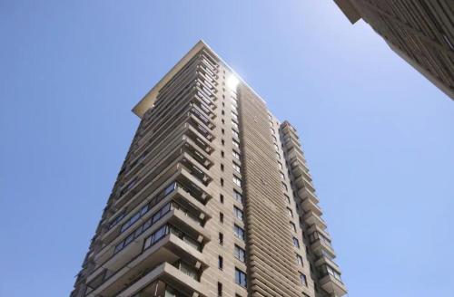 un grand bâtiment avec un ciel bleu en arrière-plan dans l'établissement Las Condes, Apartamento para 4 con Piscina, à Santiago
