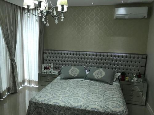 a bedroom with a large bed and a chandelier at Casa com piscina em itapema in Itapema