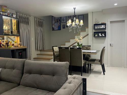 a living room with a couch and a dining room at Casa com piscina em itapema in Itapema