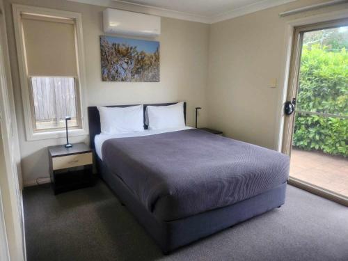 a bedroom with a large bed and a window at Cootamundra Heritage Motel & Apartments in Cootamundra
