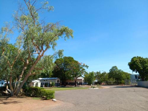 a parking lot with a tree and a house at Mt Isa Caravan Park in Mount Isa