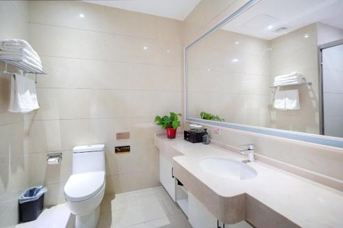 a bathroom with a toilet and a sink and a mirror at Huashan Xinyuan International Hotel in Huayin
