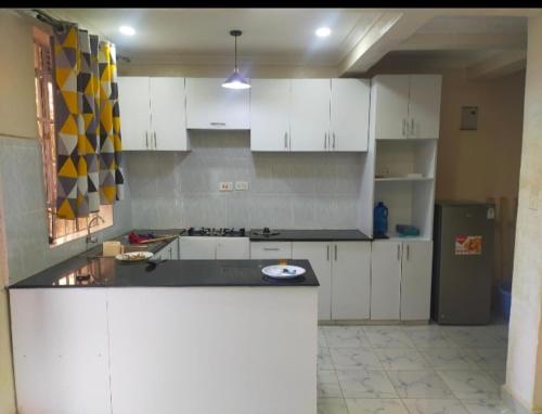 a kitchen with white cabinets and a black counter top at Golden Home in Maseno