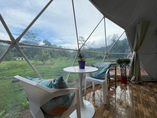 Zelt mit einem Tisch und Stühlen sowie Aussicht in der Unterkunft La Comarca River Glamping Dome near Manuel Antonio in Manuel Antonio