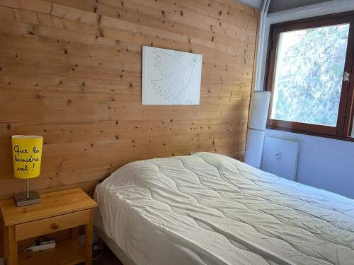 - une chambre avec des murs en bois, un lit et une lampe dans l'établissement Appartement confort proche pistes, WIFI gratuit, 8 pers, Flaine - FR-1-425-211, à Arâches-la-Frasse
