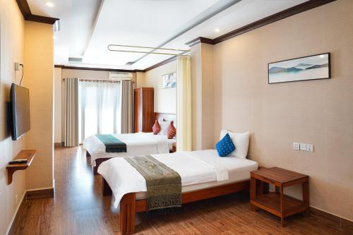 a hotel room with two beds and a tv at Phuminh Hotel Riverside in Phnom Penh