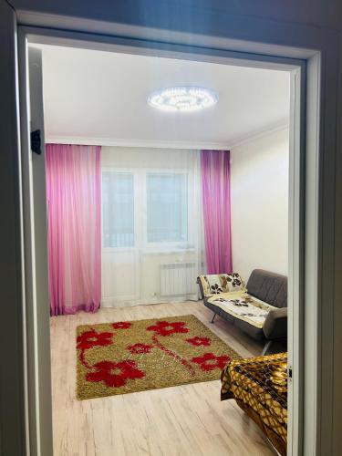 een woonkamer met roze gordijnen en een bank bij Уютная квартира в центре столицы in Taldykolʼ