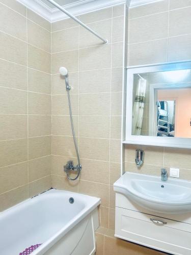 een badkamer met een bad, een wastafel en een spiegel bij Уютная квартира в центре столицы in Taldykolʼ