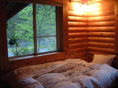 Ce lit se trouve dans une cabane en rondins dotée d'une fenêtre. dans l'établissement Mori no Kuni - Vacation STAY 03869v, à Ōma
