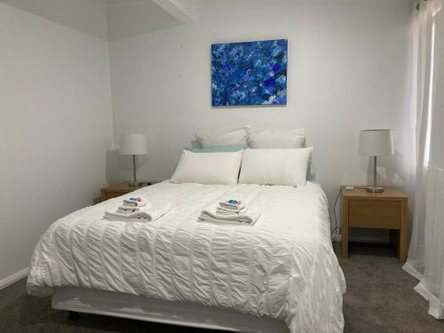 a bedroom with a white bed with two tables and a painting at Rosewhite House in Myrtleford