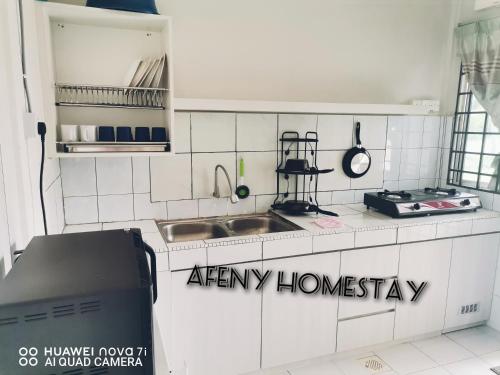 a white kitchen with a sink and a stove at Afeny Homestay in Tawau