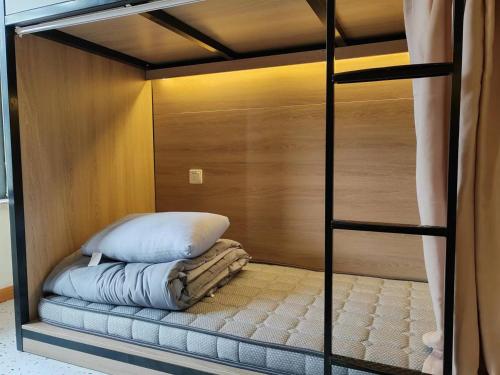 不负韶华青年旅馆 Youth Hostel في سوتشو: سرير بطابقين مع وسادة في الغرفة