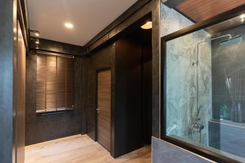 a bathroom with black walls and a glass door at Huather villa & cafe หัวเท่อวิลล่า in Ban Hin Sam Kon