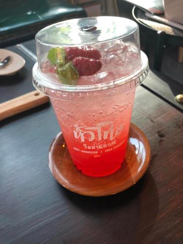 a drink in a plastic cup sitting on a wooden plate at Huather villa & cafe หัวเท่อวิลล่า in Ban Hin Sam Kon