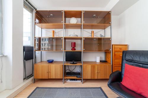 a living room with a book shelf and a tv at Shiny 1BR Flat in Fitzrovia, 2 min to Tube in London