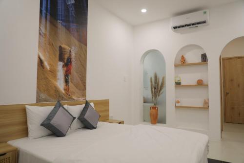 ein Schlafzimmer mit einem weißen Bett und einem Gemälde an der Wand in der Unterkunft Somo Farm Cửu Long in Vĩnh Long
