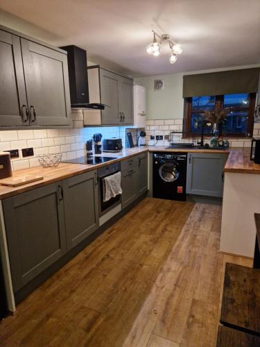 a kitchen with gray cabinets and a wooden floor at Purdie Close Holiday Let in Cheddar
