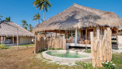 a hut with a pool in front of a house at Bleu MATHIS Gili Asahan in Gili Asahan