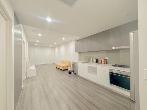 a kitchen with white cabinets and a couch in it at Burwood Cozy Apartment Free Parking in Sydney