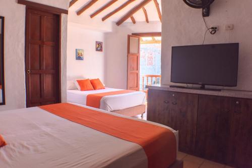 um quarto com 2 camas e uma televisão de ecrã plano em El Retiro Barichara 206 em Barichara