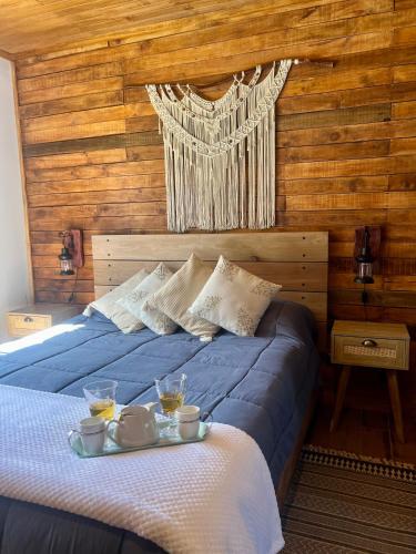 a bedroom with a blue bed with two drinks on it at Rümü in Pucón