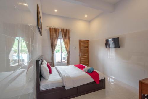 a bedroom with a bed and a tv on the wall at RedDoorz Plus @ Singaraja in Singaraja