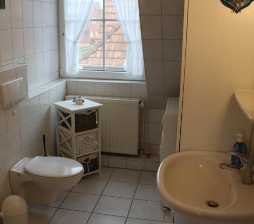 uma casa de banho com um WC e um lavatório em Ferienhaus Inselblick em Dornumersiel