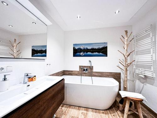 a white bathroom with a tub and a sink at Alpenglühen in Oberstaufen