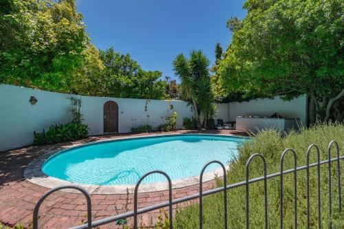een zwembad in een tuin met een hek bij Spacious family Home in Constantia with Pool in Kaapstad