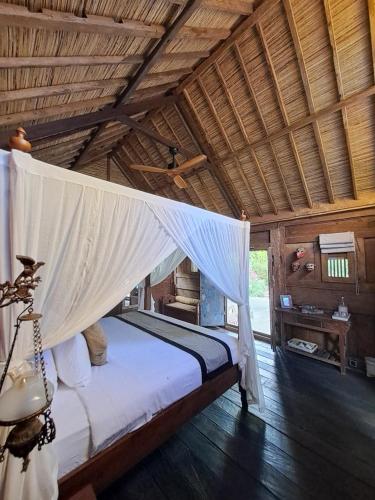 a bedroom with a bed with a mosquito net at Ayu Dira Heritage House in Ubud