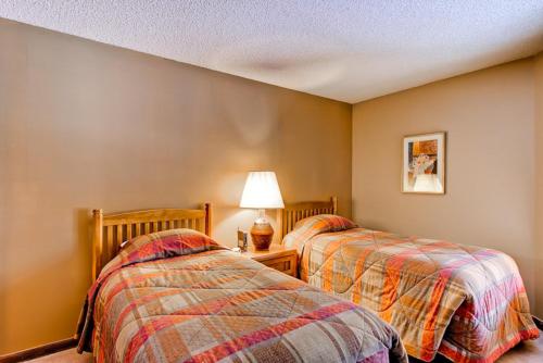 two twin beds in a room with a lamp at Tyra I A2D in Breckenridge