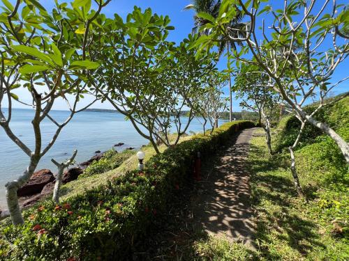 a path next to a body of water with trees at Koh Mak Buri Hut Natural Resort in Ko Mak