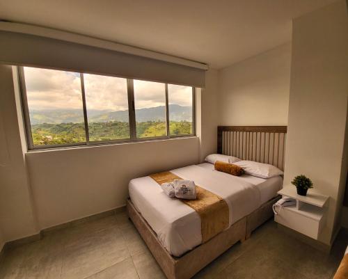 a bedroom with a bed and a large window at Hotel La Gran Estaciónag in Armenia